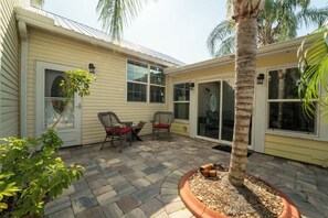 A house with a patio, two chairs, a palm tree, and a potted plant. - The Poolside Cottage -Wifi,Pool (Jacksonville)