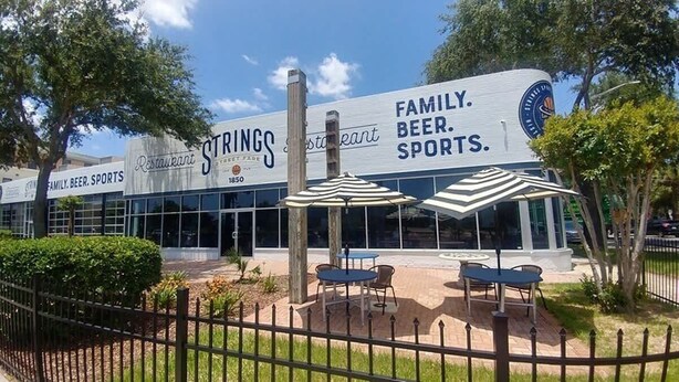 A restaurant with outdoor seating, a sign reading 'FAMILY. BEER. SPORTS.', and a logo with a baseball cap. - Historic bungalow - Wifi, Yard, Cozy (Jacksonville)