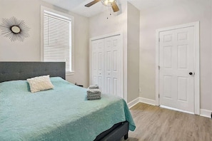 A bedroom with a bed, a ceiling fan, a window with blinds, and a door. - Historic bungalow - Wifi, Yard, Cozy (Jacksonville)