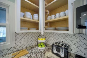 A kitchen with wooden cabinets, a fruit basket, a toaster, and a window. - "Sea Grape Villa" Pool/ Ping Pong, (Jacksonville Beach)