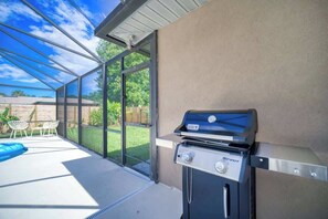 A covered outdoor area with a barbecue grill, a pool, and a patio with chairs. - "Sea Grape Villa" Pool/ Ping Pong, (Jacksonville Beach)