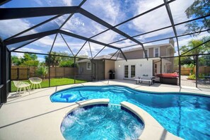 A swimming pool with a hot tub, surrounded by a covered patio with chairs and a table. - "Sea Grape Villa" Pool/ Ping Pong, (Jacksonville Beach)