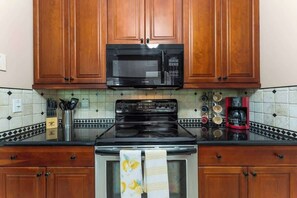 A kitchen with wooden cabinets, a microwave, a stove, and a coffee maker. - Coastal Lane - Entire (Jacksonville)