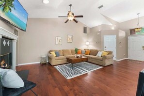 A living room with a sofa set, a coffee table, a fireplace, and a ceiling fan. - Coastal Lane - Entire (Jacksonville)