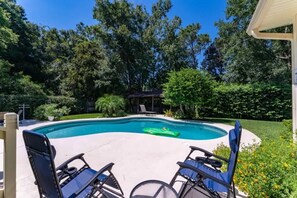 A swimming pool with a curved edge, surrounded by a patio area with chairs and a small covered structure. - Coastal Lane - Entire (Jacksonville)