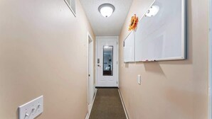 Ein Flur mit Teppichboden, einer weißen T ür und einer Tafel an der Wand.