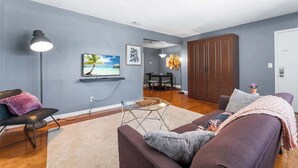 Un salon avec un canapé, une table basse et un téléviseur fixé au mur.