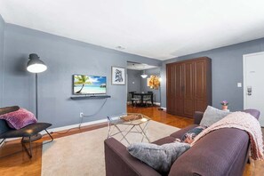 Ein Wohnzimmer mit einer Couch, einem Couchtisch und einem an der Wand montierten Fernseher.