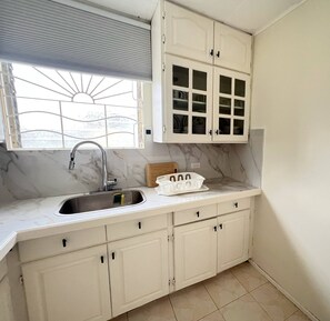A kitchen with a sink, cabinets, and a window with a view.