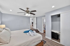 Une chambre à coucher avec un lit, un ventilateur de plafond et un dressing.
