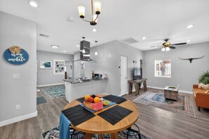 A modern living room with a dining area, a kitchen, and a ceiling fan. - The Phoenix Haven | Luxury 2BR Near Banner & Chase (Phoenix)
