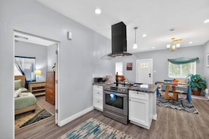 A modern kitchen with white cabinetry, a central island, and a black range hood. - The Phoenix Haven | Luxury 2BR Near Banner & Chase (Phoenix)
