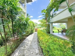 Ein Weg, gesäumt von üppiger Vegetation, mit einem Gebäude mit Balkon.