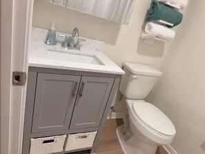A bathroom with a white sink, a toilet, and a mirror above the sink. - Furnished Apartment l League City l Business & Medical Travelers (Dickinson)