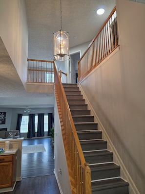 A multi-level home interior with a staircase, wooden railings, and a pendant light fixture. - Delmar Paradise !! Spacious 4-bedroom house in peaceful Delmar with, POOL, AC. (Delmar)