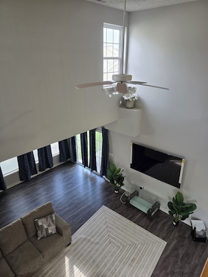 A spacious living room with a ceiling fan, a flat-screen TV mounted on the wall, a sofa, and a coffee table. - Delmar Paradise !! Spacious 4-bedroom house in peaceful Delmar with, POOL, AC. (Delmar)