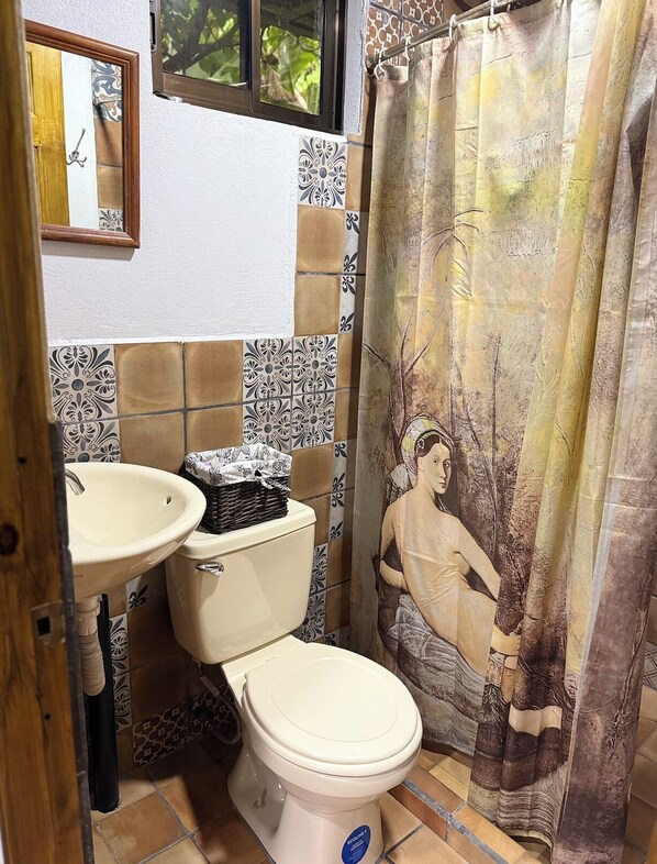 Een badkamer met toilet, wastafel en douchegordijn.