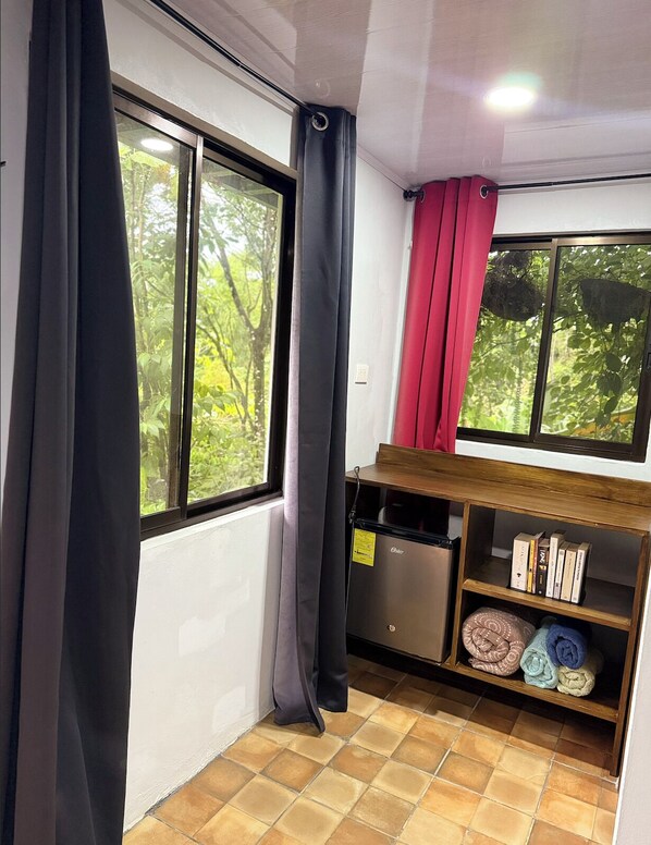 Ein kleiner Raum mit Fenster, einem Regal mit Büchern und Handtüchern sowie einem kleinen Gerät.