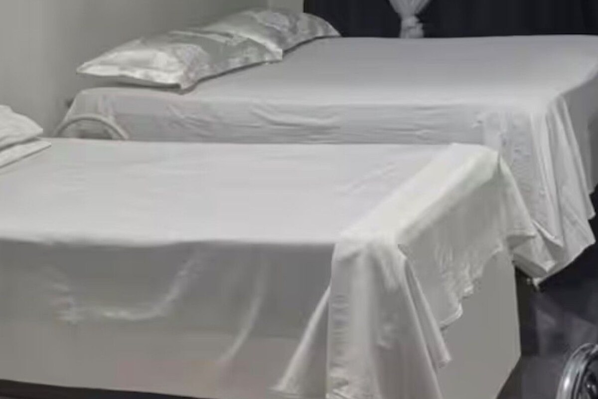 A room with two beds, a framed picture on the wall, and a curtain.
