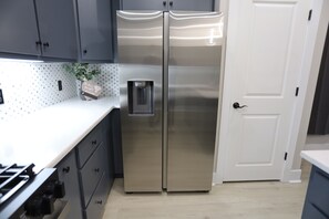 Ein Edelstahl-Kühlschrank mit zwei Türen, ein Wasserhahn, eine weiße Arbeitsplatte und eine Tür mit Griff.