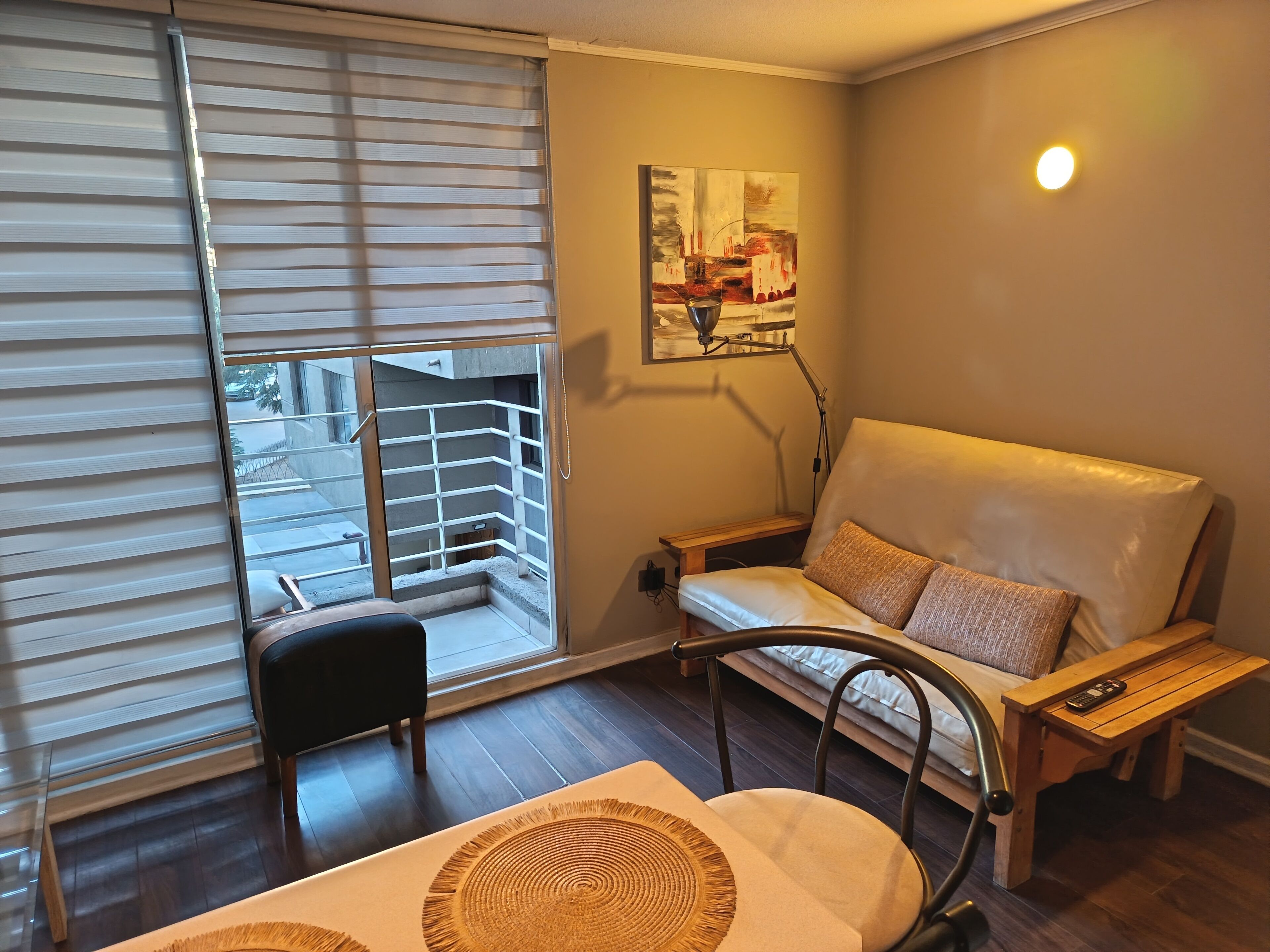 Une pièce avec une porte-fenêtre coulissante, un canapé, une petite table et un tableau au mur.
