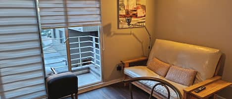 Una habitación con puerta corrediza de vidrio, un sofá, una mesita y un cuadro en la pared.