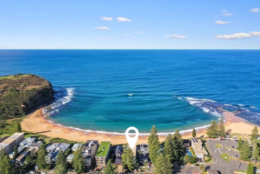 A coastal property with a beach, ocean view, and a residential area with houses and a parking lot.