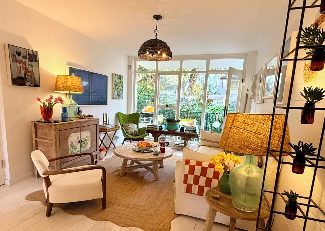 A living room with a sofa, chairs, a coffee table, and a view through large windows.