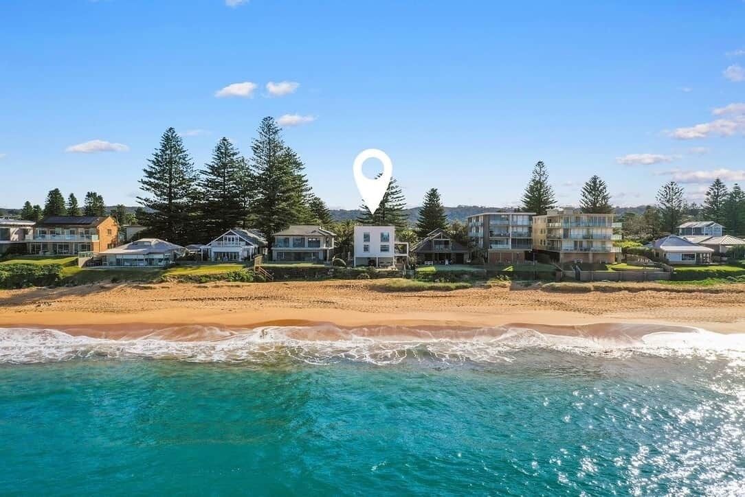 A beachfront property with multiple houses, a sandy beach, and a clear view of the ocean.