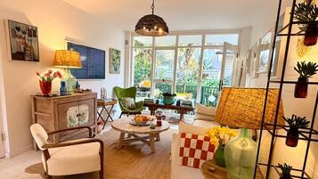 Een zithoek met een bank, fauteuil, salontafel en uitzicht op het omliggende landschap.