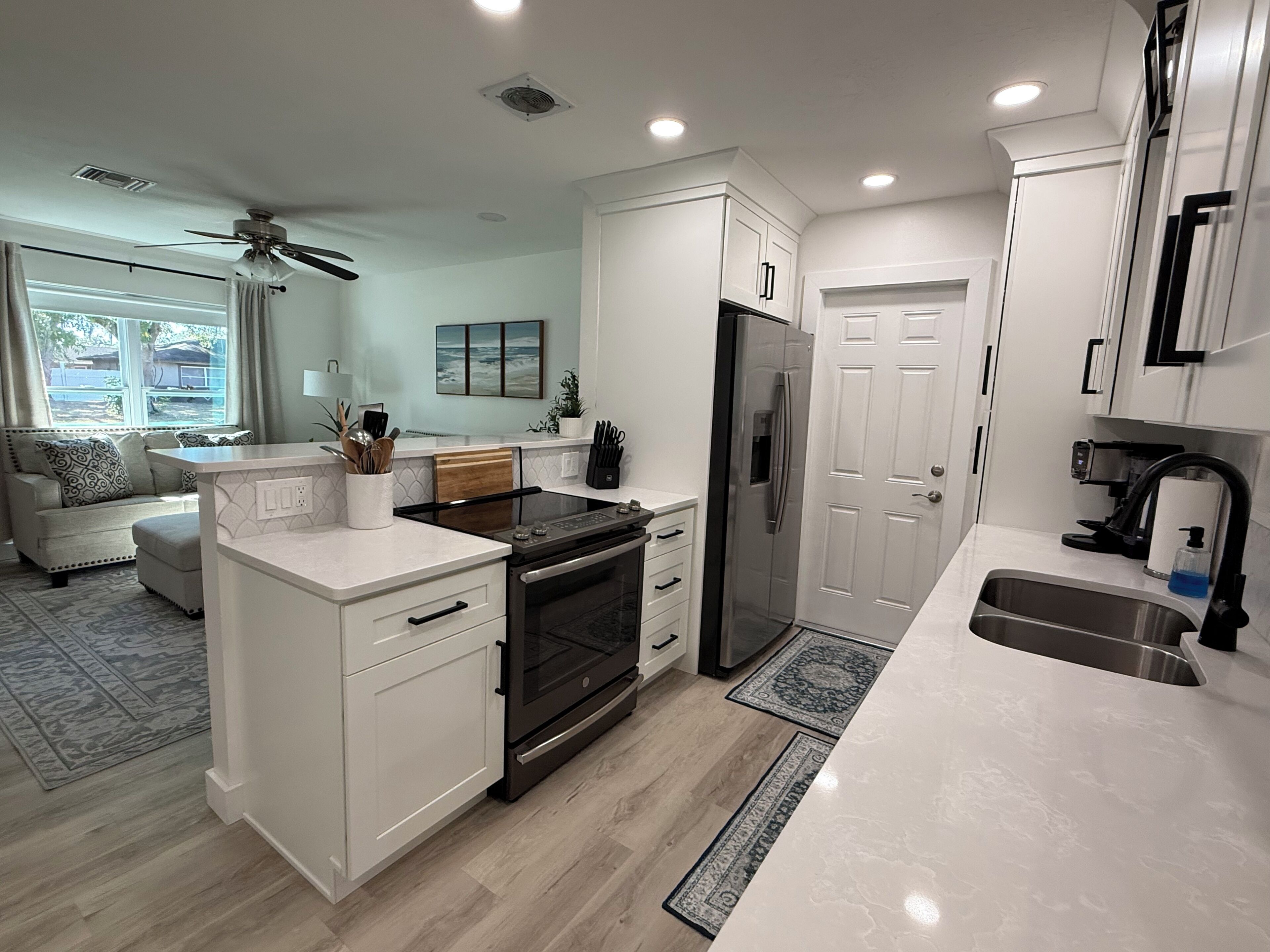 A modern kitchen with white cabinetry, a built-in oven, and a stainless steel refrigerator.