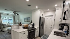 A modern kitchen with white cabinetry, a built-in oven, and a stainless steel refrigerator.