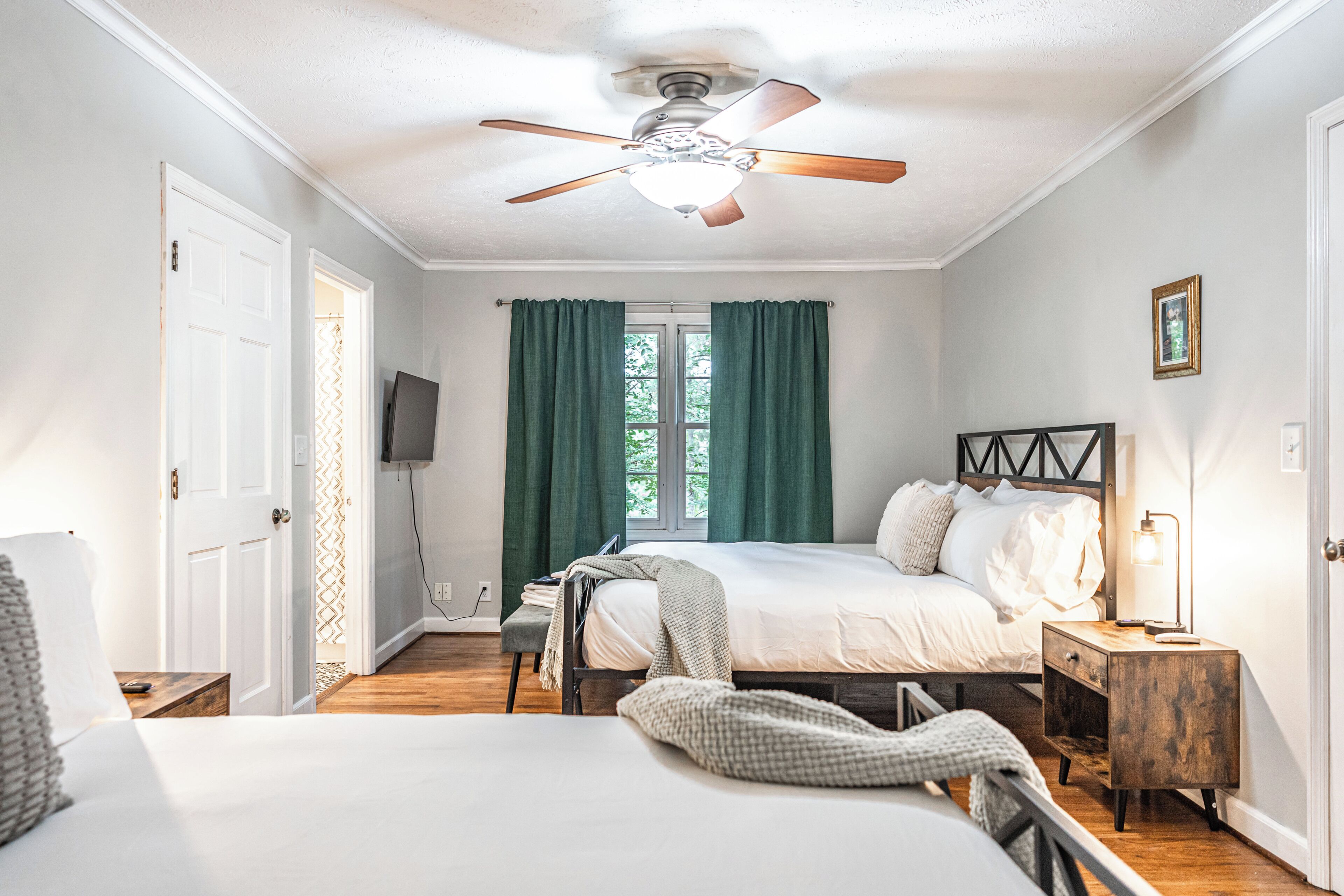 A bedroom with a bed, bedside table, lamp, and a ceiling fan.