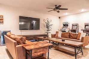 Ein Wohnzimmer mit einer Couch, einem Couchtisch, einem Fernseher und zwei Spielautomaten.