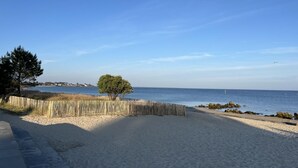 Ein Strand mit einer Holzlattenveranda, einem Baum und einem strahlend blauen Himmel.
