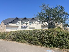 Um edifício com fachada de pedra, várias varandas e uma árvore na frente.