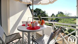 Ein Balkon mit Tisch, gedeckt für ein Frühstück, inklusive Obstschale, Teekanne und Krug.
