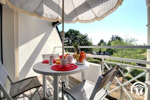 A balcony with a table set for breakfast, including a fruit bowl, a teapot, and a pitcher. - Cat Oceania 2 - CARNAC (CARNAC)