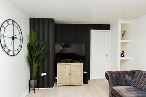 Ein Wohnzimmer mit Fernseher, Schrank, Sofa und einem Blumentopf.