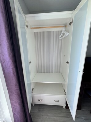 A walk-in closet with a hanging rod, two drawers, and a striped back panel. - The Normandy House -New Modern 3 Bedrooms 2 Bathroom retreat in Stuart (Stuart)