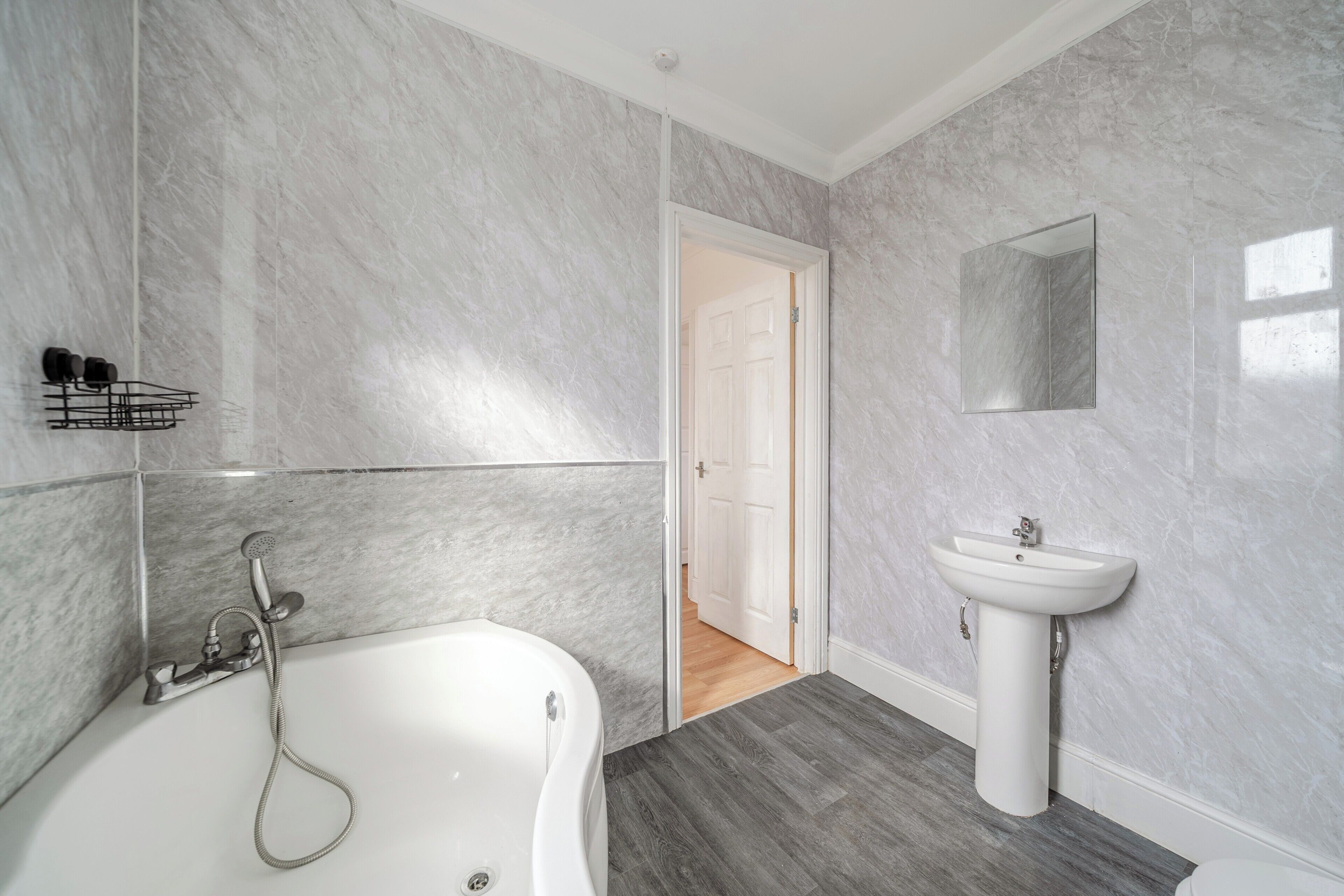 A bathroom with a bathtub, a sink, and a mirror on the wall.
