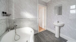 A bathroom with a bathtub, a sink, and a mirror on the wall.