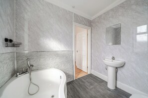 A bathroom with a bathtub, a sink, and a mirror on the wall.