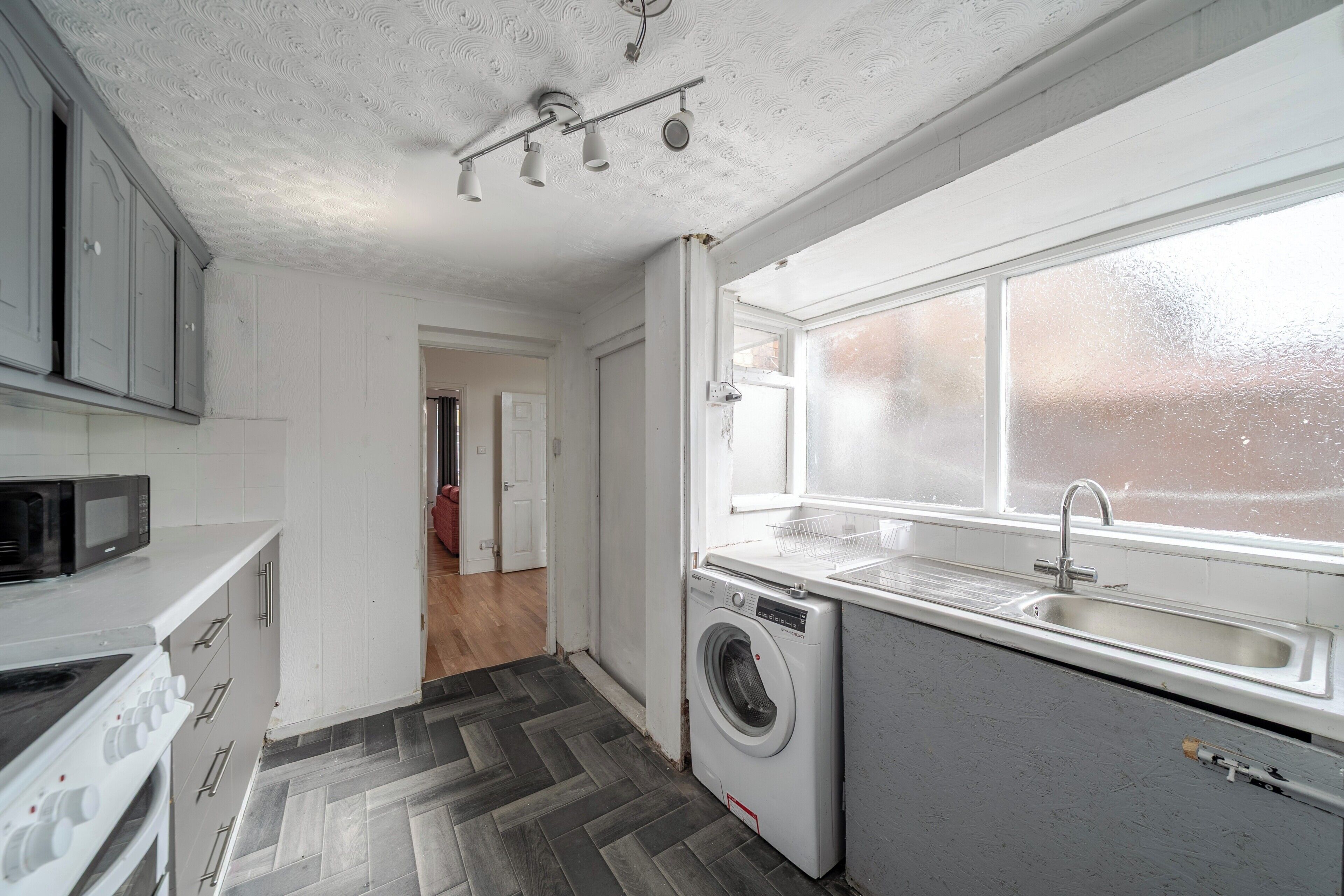 A kitchen with a washing machine, a microwave, and a sink.
