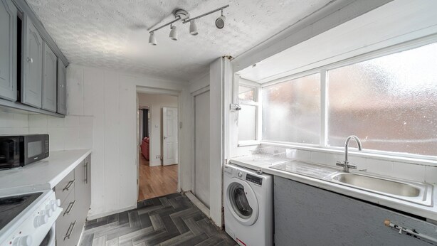 A kitchen with a washing machine, a microwave, and a sink.