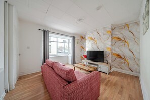 A living room with a sofa, a TV, and a wall with a marble pattern.