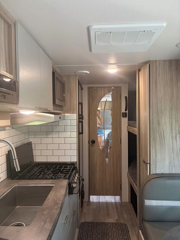 A compact kitchenette with a gas stove, sink, and wooden cabinets.