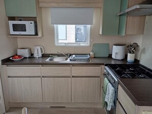 A compact kitchen with a microwave, toaster, sink, and stove.