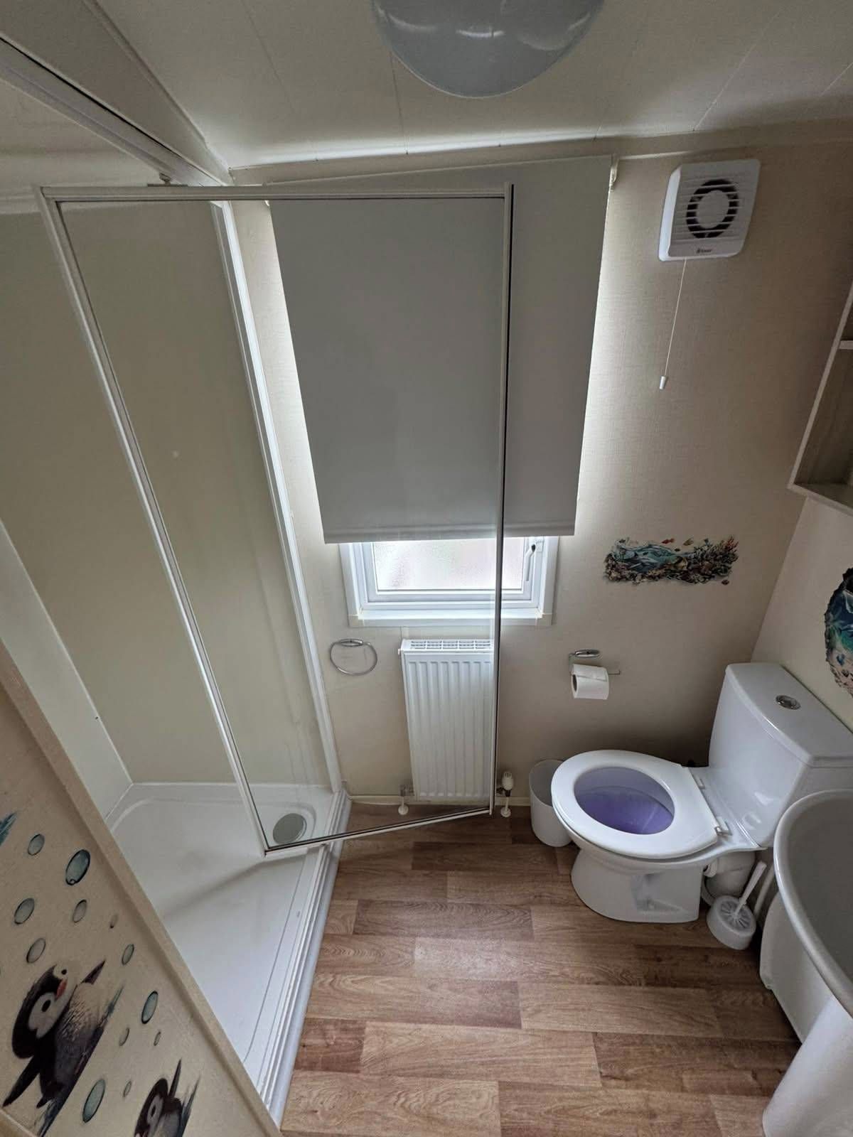A small, compact bathroom with a toilet, bidet, and a window.