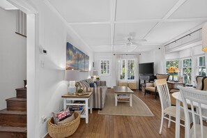 A spacious living room with a ceiling fan, a large painting, and a television. - Downtown Rehoboth Beach House Quick Walk to Beach Pets Permitted (Rehoboth Beach)